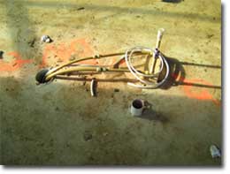 Photo of an electrical conduit and waste pipe in a concrete slab.