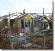 Photo of a house under construction with a temporary fence around it.