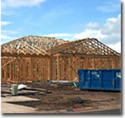 Photo of a waste bin in front of a timber house frame.