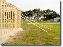 Photo of timbers leaning against an external wall frame to provide temporary bracing.