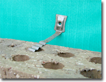 Photo of a brick tie attaching a brick to a timber frame.