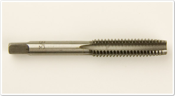 Photo showing a shaft shaped thread cutting tool with external teeth at one end and a square drive at the other